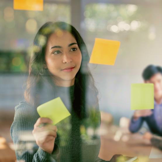 A young woman putting sticky notes on a glass.