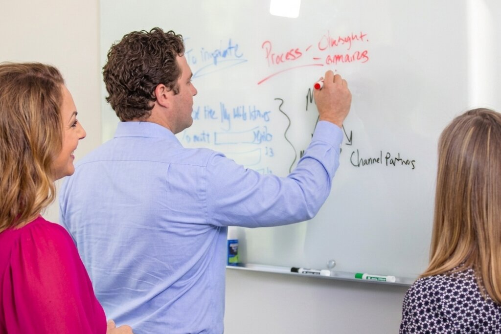 Sparkhound team member mapping strategy on a whiteboard with two colleagues